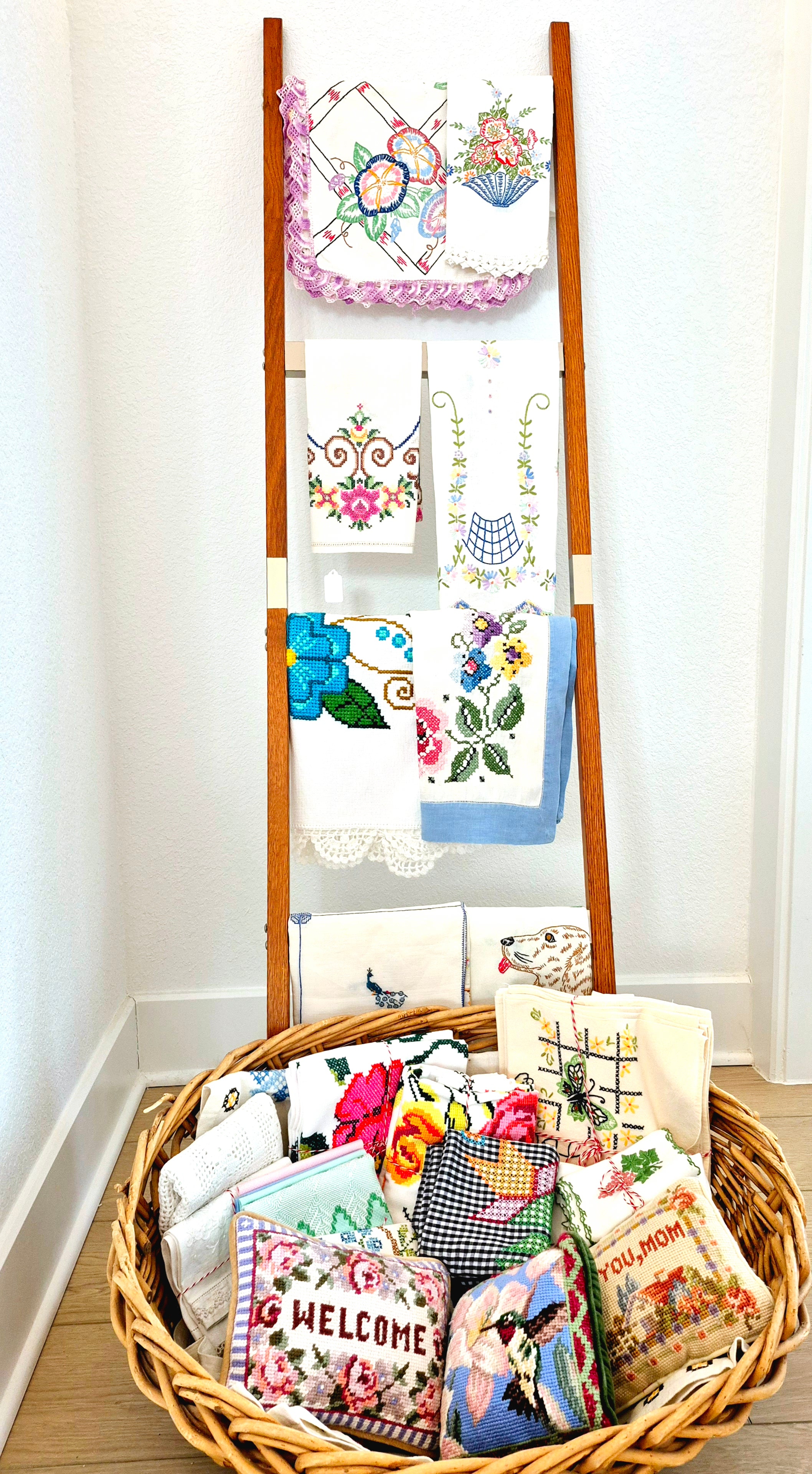Embroidered linens and floral table cloths hung over a wooden rack