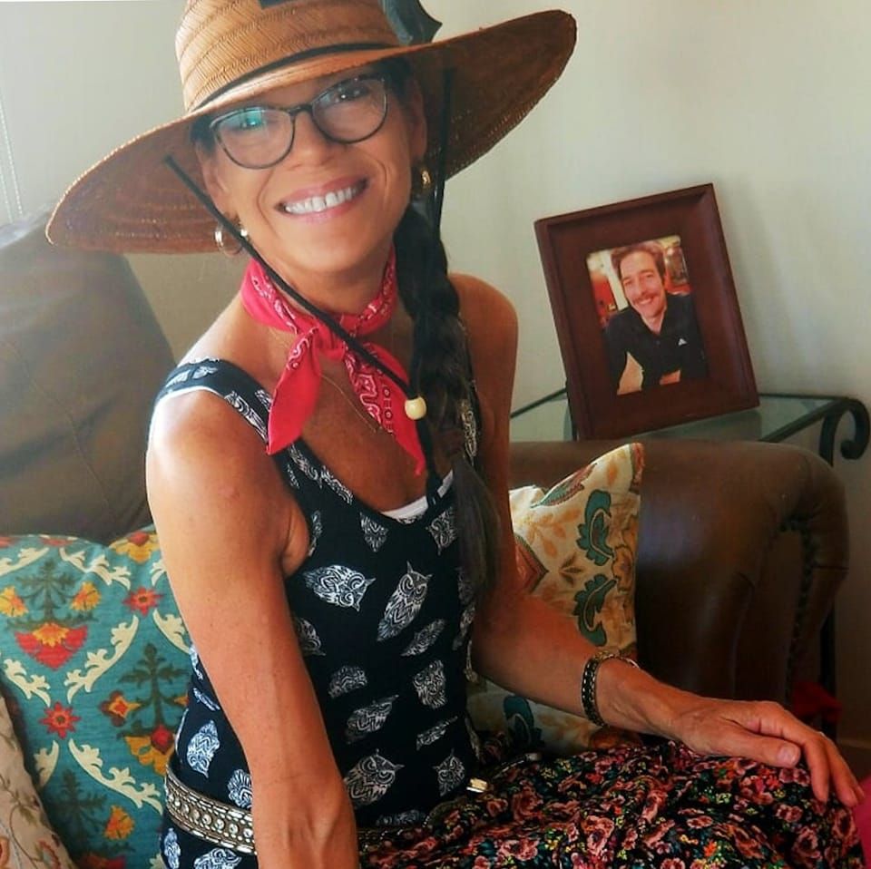 Martha seated at home wearing a wide-brimmed hat and red scarf