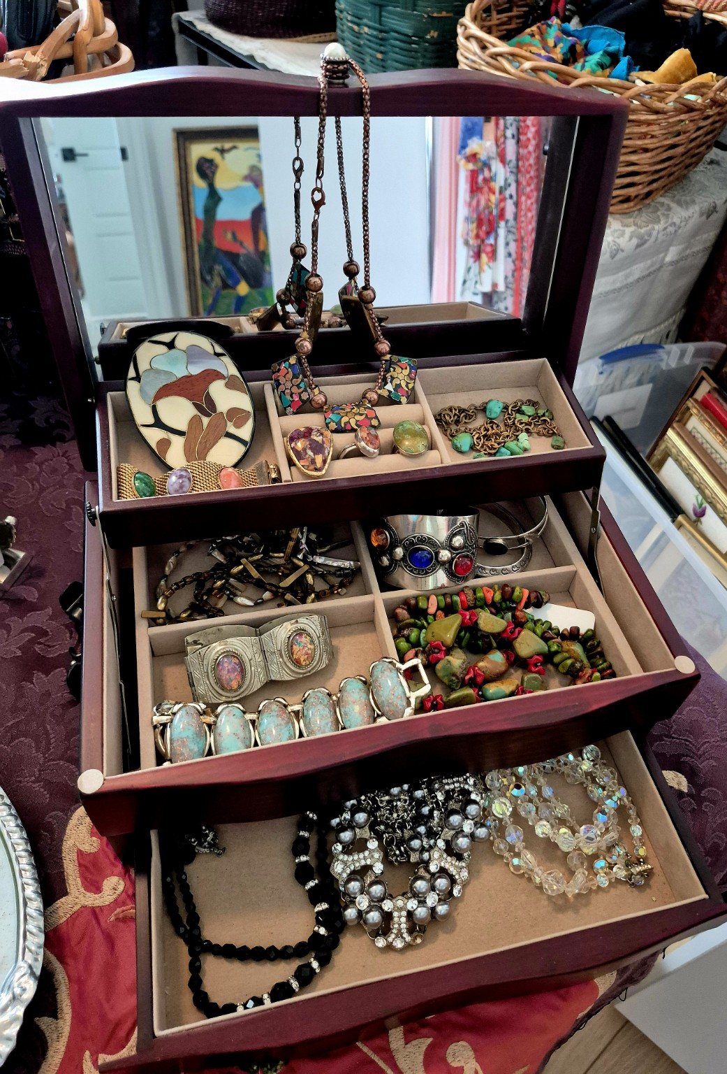 A wooden drawer filled with colorful vintage jewelry
