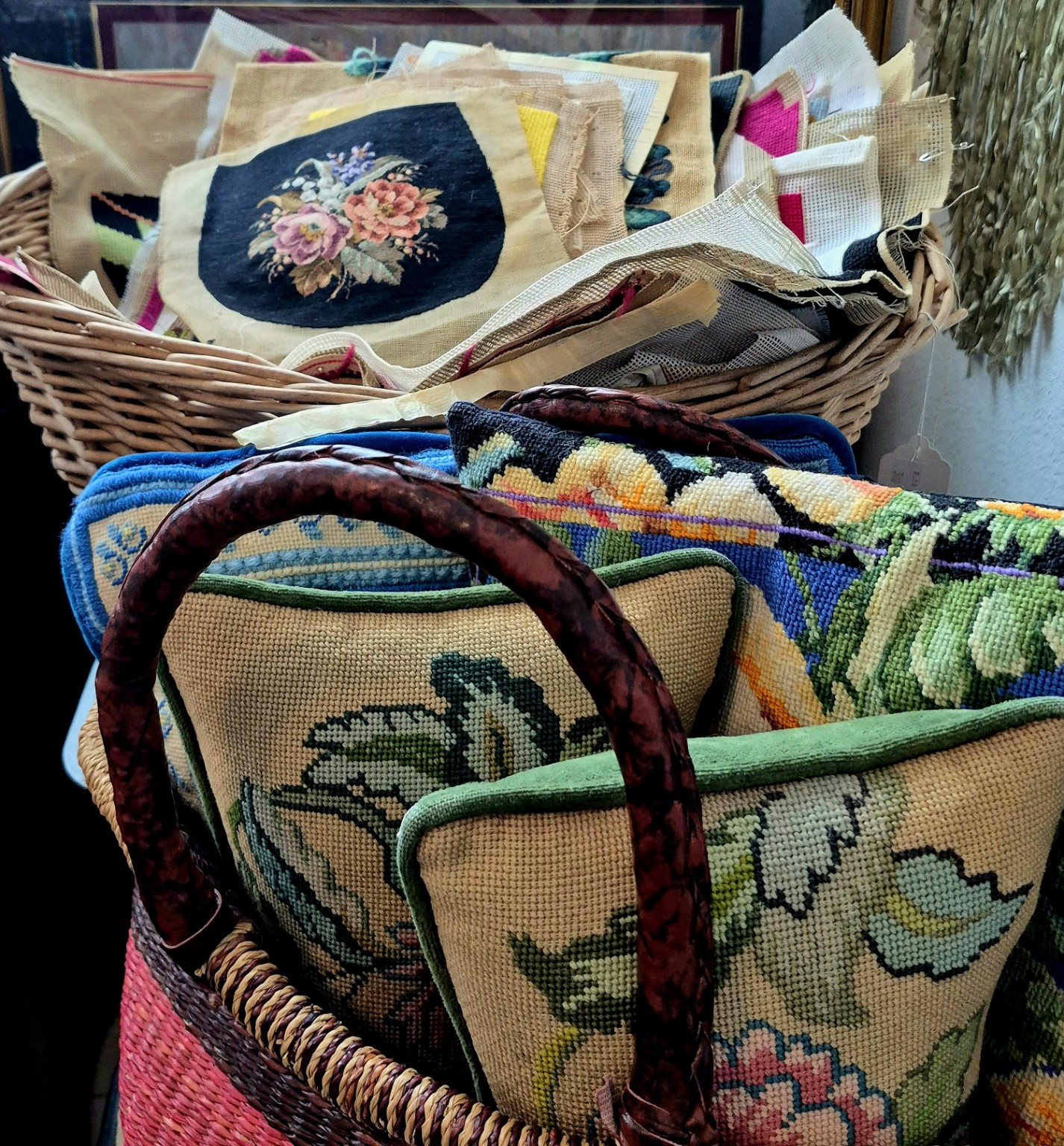 Needlepoint textiles and bags gathered in woven baskets